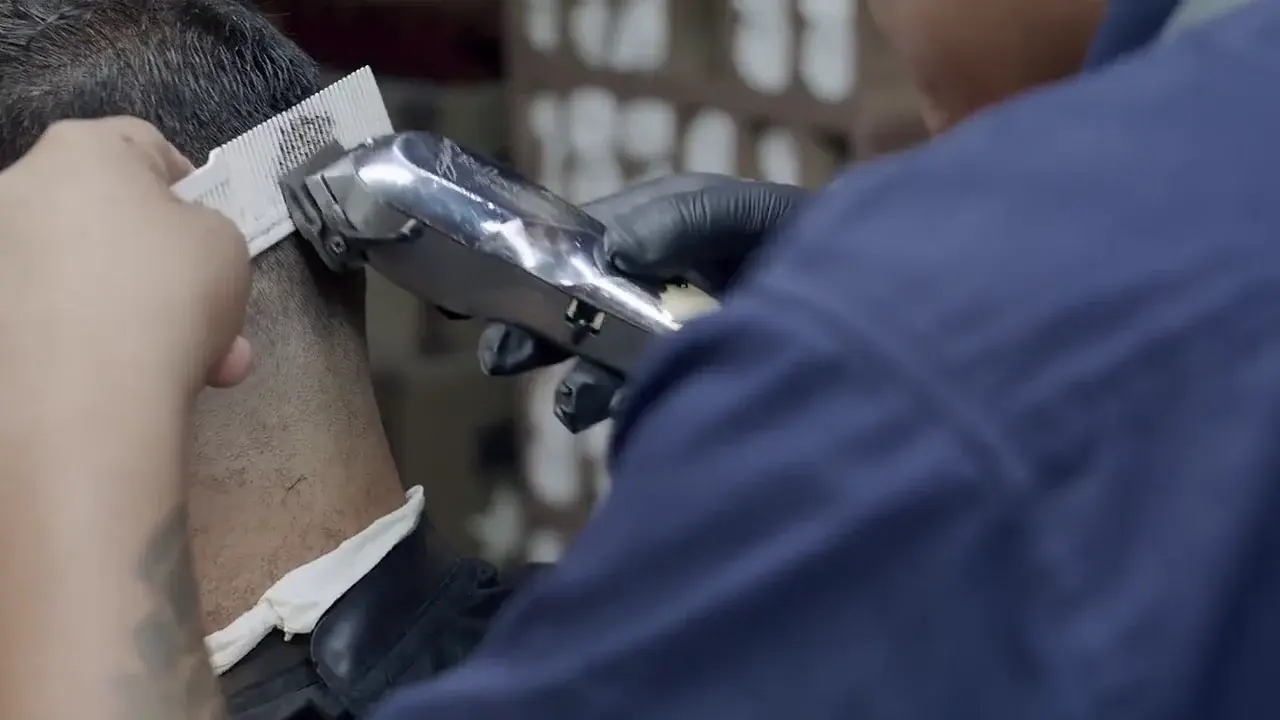 A barber finishing a fade with clippers and a comb